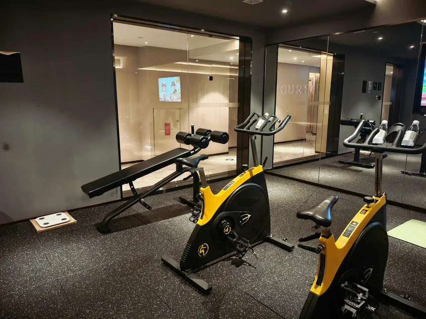 An adjustable weight bench standing beside exercise bikes in a dimly lit gym