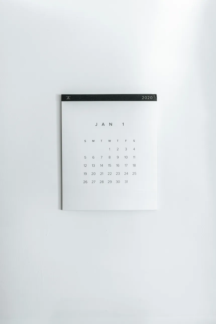 A small paper calendar hanging on a plain white wall