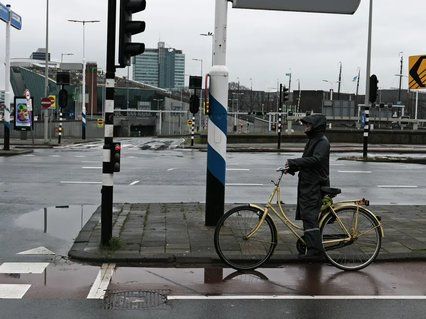 A rider waiting at a crossing beside their machine, the moment that sends people looking for a third wheel