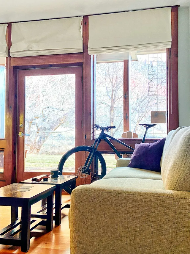 A bicycle standing in a bright living room beside a sofa and a low table