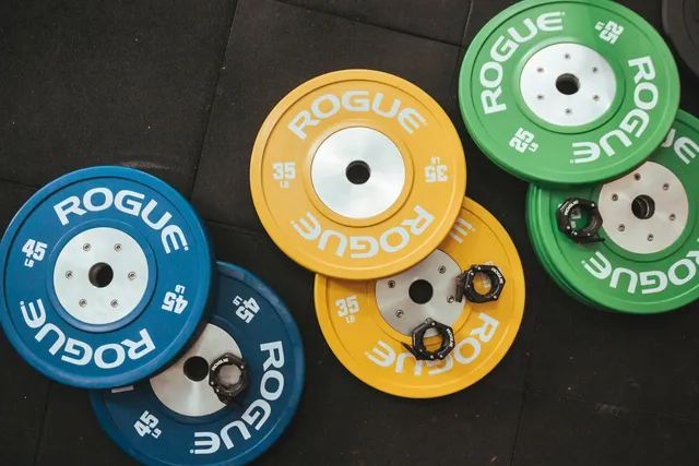 Coloured rubber bumper plates stacked in a loose pile on a gym floor