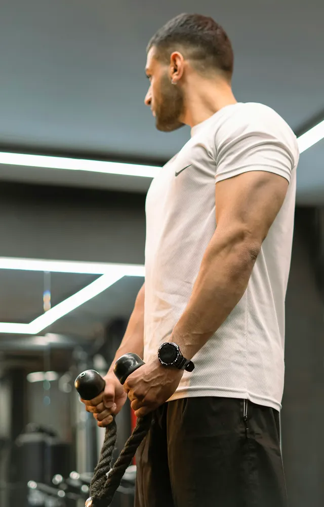 A man mid-pull on a cable machine, arms drawn back and elbows well behind his torso