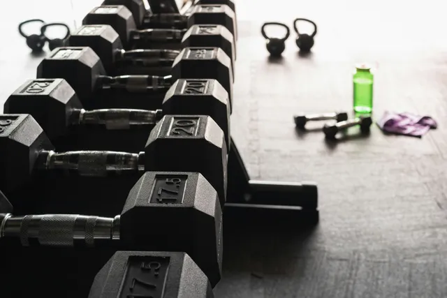 A row of fixed dumbbells and kettlebells on a gym floor
