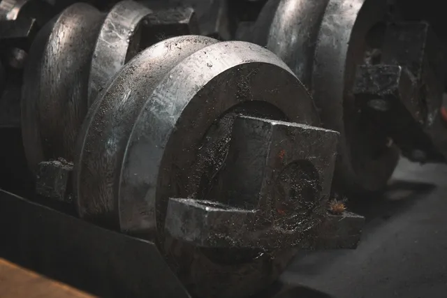 A close-up of heavy machinery parts, the metal worn smooth and darkened with use