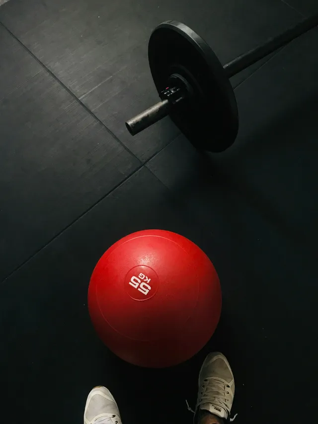 A single adjustable dumbbell resting on a dark floor, set to one of the many weights it can hold